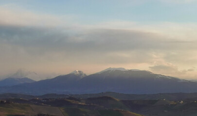 Fototapeta na wymiar Montagne dalle cime innevate dell’Appennino e valli illuminate dal sole invernale