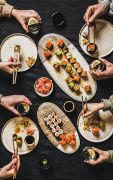 Flat-lay of people eating various sushi during japanese lockdown dinner