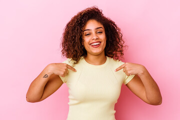 Young african american woman isolated on pink background surprised pointing with finger, smiling broadly.