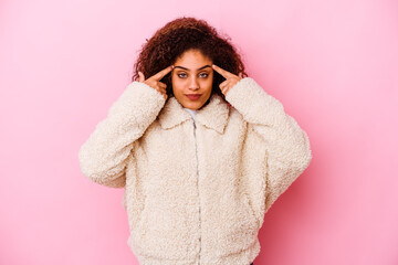 Young african american woman isolated on pink background focused on a task, keeping forefingers pointing head.