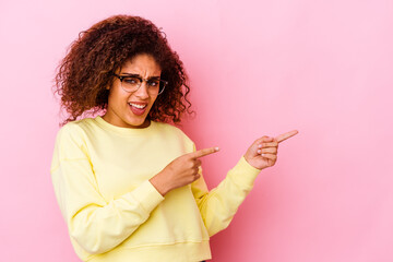 Young african american woman isolated on pink background pointing with forefingers to a copy space, expressing excitement and desire.