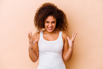Young african american woman isolated on beige background screaming with rage.