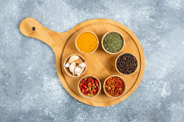 Small bowls of spices on wooden board