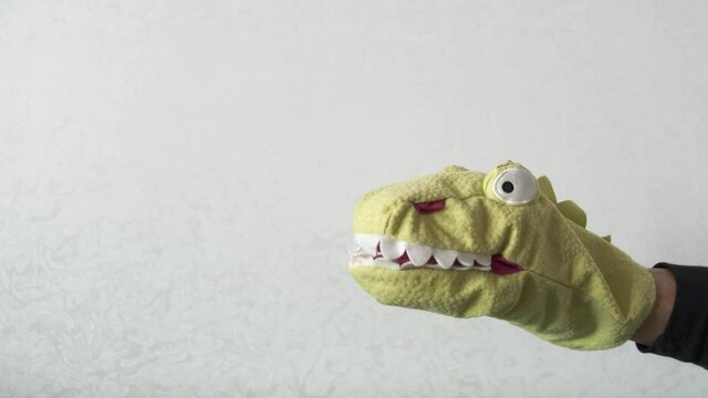 Close up toy dragon for puppet theater. Hand with funny soft doll reptiloid alien from conspiracy theories.