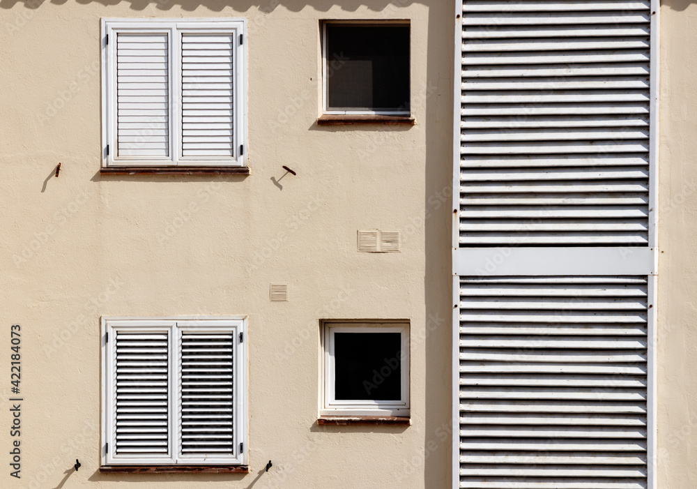 Poster facade of a minimalistic building with white window shutters on a sunny day