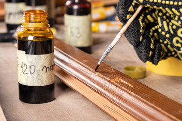 the master paints the place of the defect on the wooden door with varnish, restoration of an old...