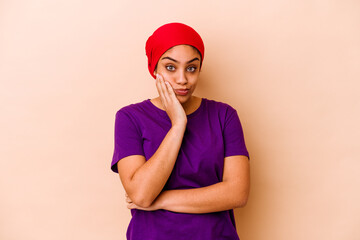 Young african american woman isolated on beige background blows cheeks, has tired expression....