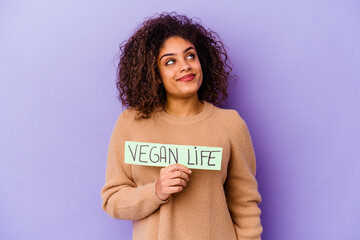 Young African American woman holding a Vegan life placard isolated dreaming of achieving goals and purposes