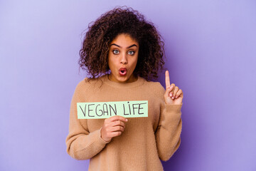 Young African American woman holding a Vegan life placard isolated having some great idea, concept of creativity.