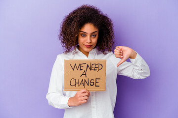 Young African American woman holding a We need a change placard isolated on purple background...