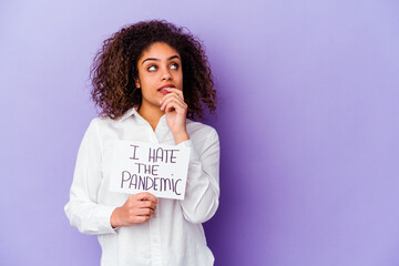 Young African American woman holding I hate pandemic placard isolated on purple background relaxed...