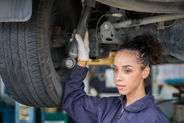 Mechanic female maintain car shock-up and wheel on hydraulic lift in car garage