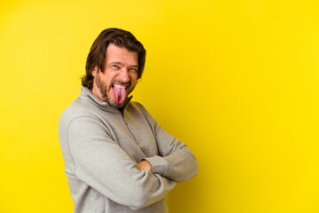 Middle age caucasian man isolated on yellow background funny and friendly sticking out tongue.