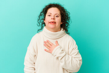 Woman with Down syndrome isolated laughs out loudly keeping hand on chest.