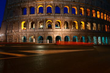 Fototapeta premium No people on the street near Colosseum in Rome . Famous architecture illuminated in the night . Empty italian street 