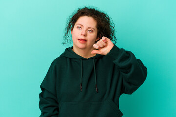 Woman with Down syndrome isolated showing thumb down and expressing dislike.