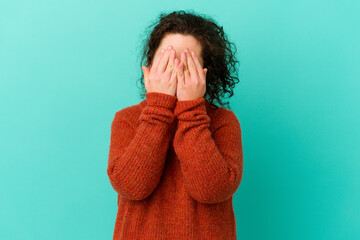Woman with Down syndrome isolated blink through fingers frightened and nervous.