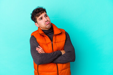 Young caucasian man isolated on blue background tired of a repetitive task.