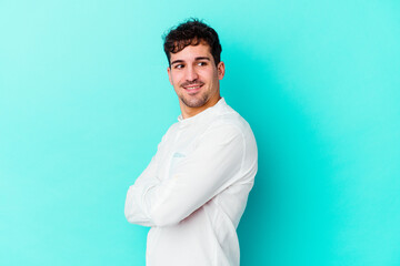 Young caucasian man isolated on blue background laughing and having fun.