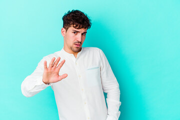 Young caucasian man isolated on blue background being shocked due to an imminent danger