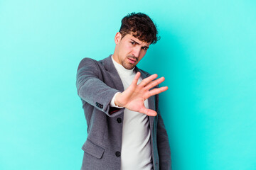 Young caucasian man isolated on blue background rejecting someone showing a gesture of disgust.