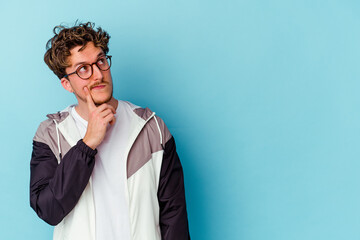 Obraz premium Young caucasian man wearing eyeglasses isolated on blue background looking sideways with doubtful and skeptical expression.