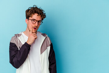 Young caucasian man wearing eyeglasses isolated on blue background looking sideways with doubtful and skeptical expression.