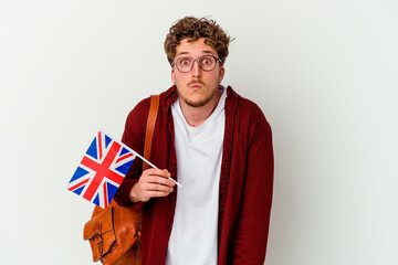 Young student man learning english isolated on white background shrugs shoulders and open eyes confused.