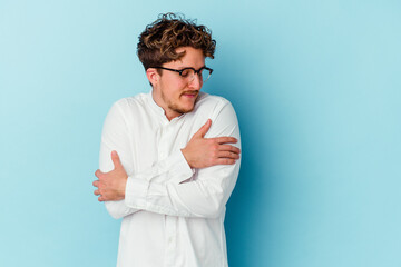 Young caucasian business man isolated on blue background hugs, smiling carefree and happy.