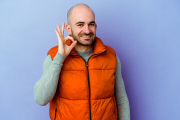 Young caucasian bald man isolated on purple background cheerful and confident showing ok gesture.