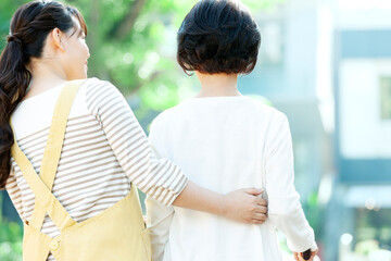 シニア女性の歩行を介助する女性介護士の後ろ姿