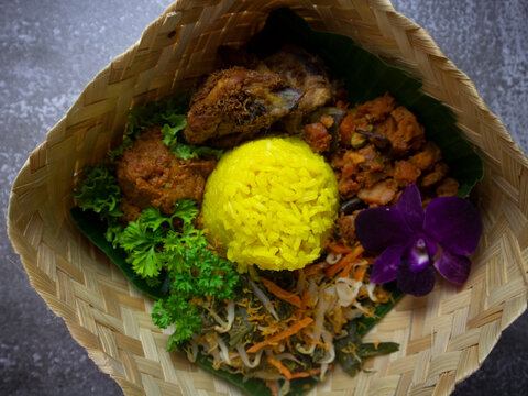 Nasi Kuning (Yellow Rice) Flatlay with Copy Space. Nasi Tumpeng (Indonesian yellow rice) in a Bamboo Woven Basket. 