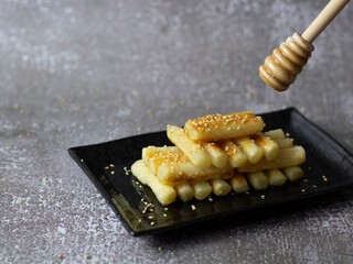Korean Rice Cakes with Honey (Garaetteok). Dripping honey on tteokbokki (Korean rice cake).