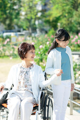 車椅子に乗った祖母と手を繋ぐ孫娘