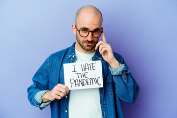 Young caucasian bald man holding a I hate the pandemic placard isolated on blue background pointing...