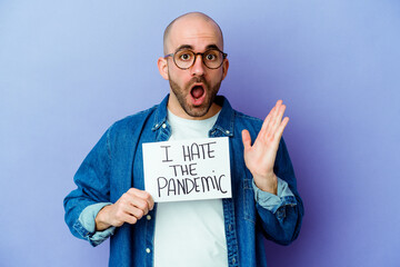 Young caucasian bald man holding a I hate the pandemic placard isolated on blue background surprised and shocked.