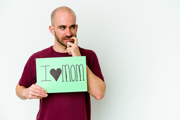 Young caucasian bald man holding a I love mom placard isolated on yellow background relaxed...