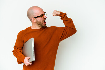 Young bald man holding a laptop isolated on white background raising fist after a victory, winner...