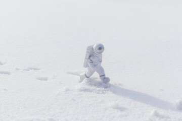 Statuette of an astronaut confidently explores alien planet's surface. Cold planet covered with snow. © Smile