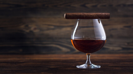Cognac and cigar. Glass of cognac or brandy with cigars from Cuba Havana on natural wooden...