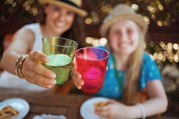 Smiling mother and child clinking glasses and having brunch