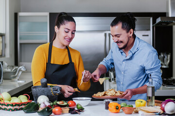 mexican couple cooking and eating mexican food sauce together in their kitchen at home in Mexico city