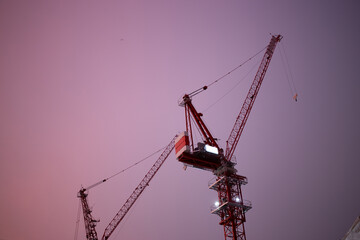 Construction site with cranes in sunset sky.