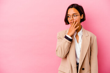 Young business mixed race woman isolated on pink background thoughtful looking to a copy space covering mouth with hand.