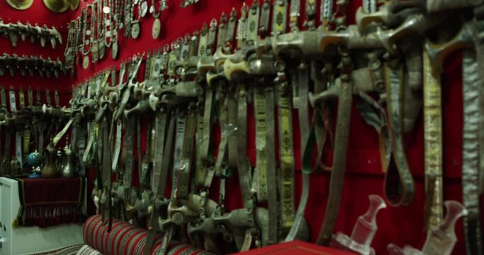 Knives, daggers, and swords on sale at Nizwa Souq marketplace, Oman, medium shot