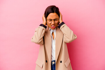 Fototapeta premium Young business mixed race woman isolated on pink background covering ears with hands.