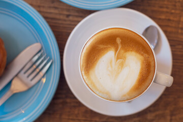 Top view Close up hot cappuccino, latte on table with blur coffee shop background. Hot cappuccino coffee on wood table with blur brakefast background. breakfast at coffee shop soft focus select coffee