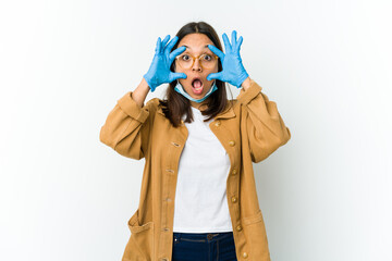 Young latin woman wearing a mask to protect from covid isolated on white background keeping eyes opened to find a success opportunity.