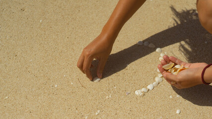hand playing with seashells on sand