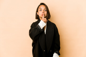 Young hispanic woman isolated keeping a secret or asking for silence.